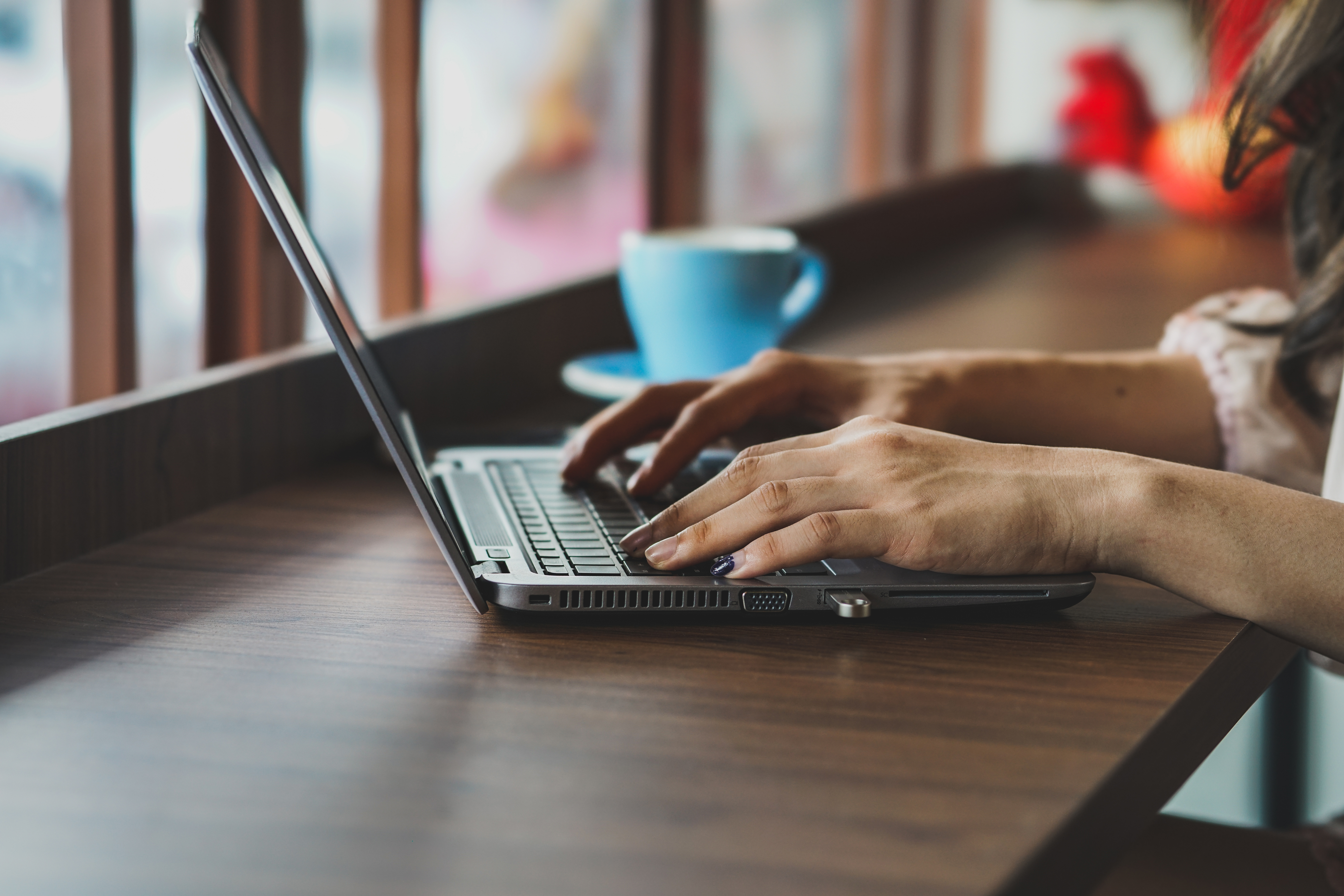 cropped-hands-woman-using-laptop-table-cafe