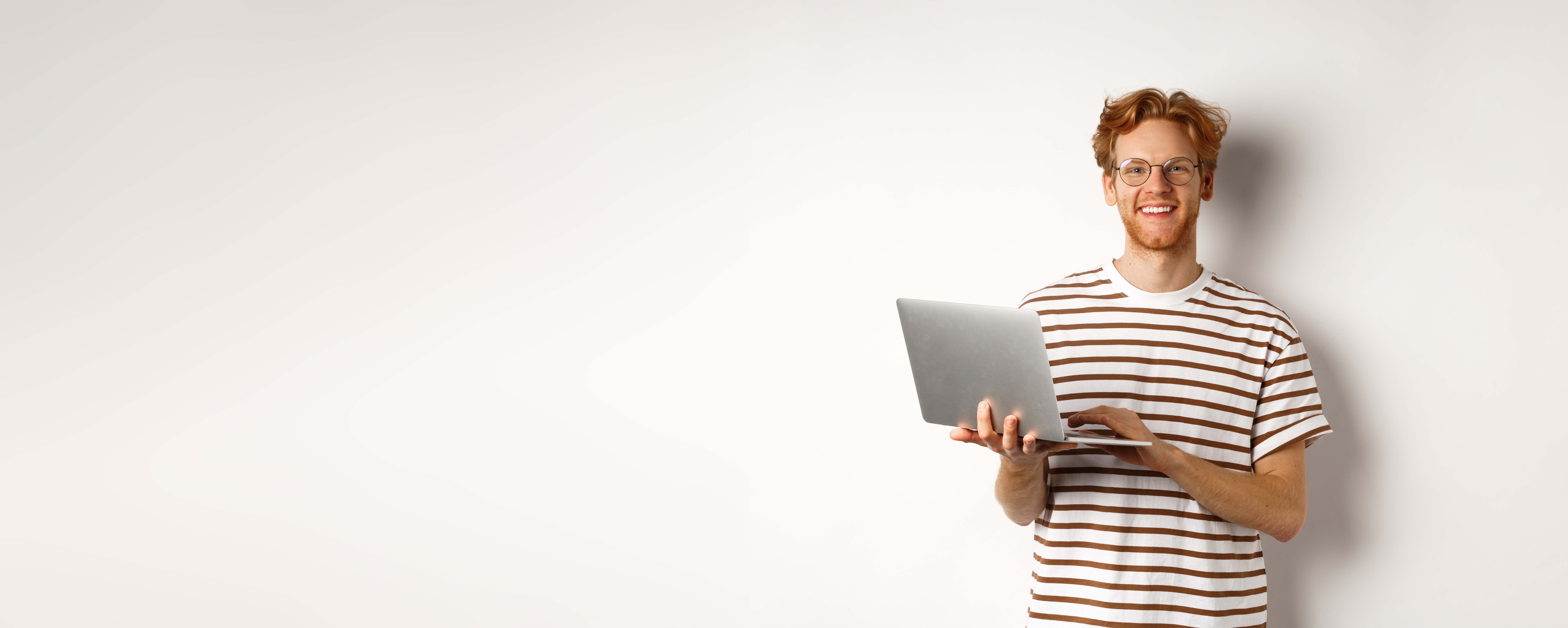 smiling-young-man-working-on-laptop-and-looking-joyful-standing-over-white-background
