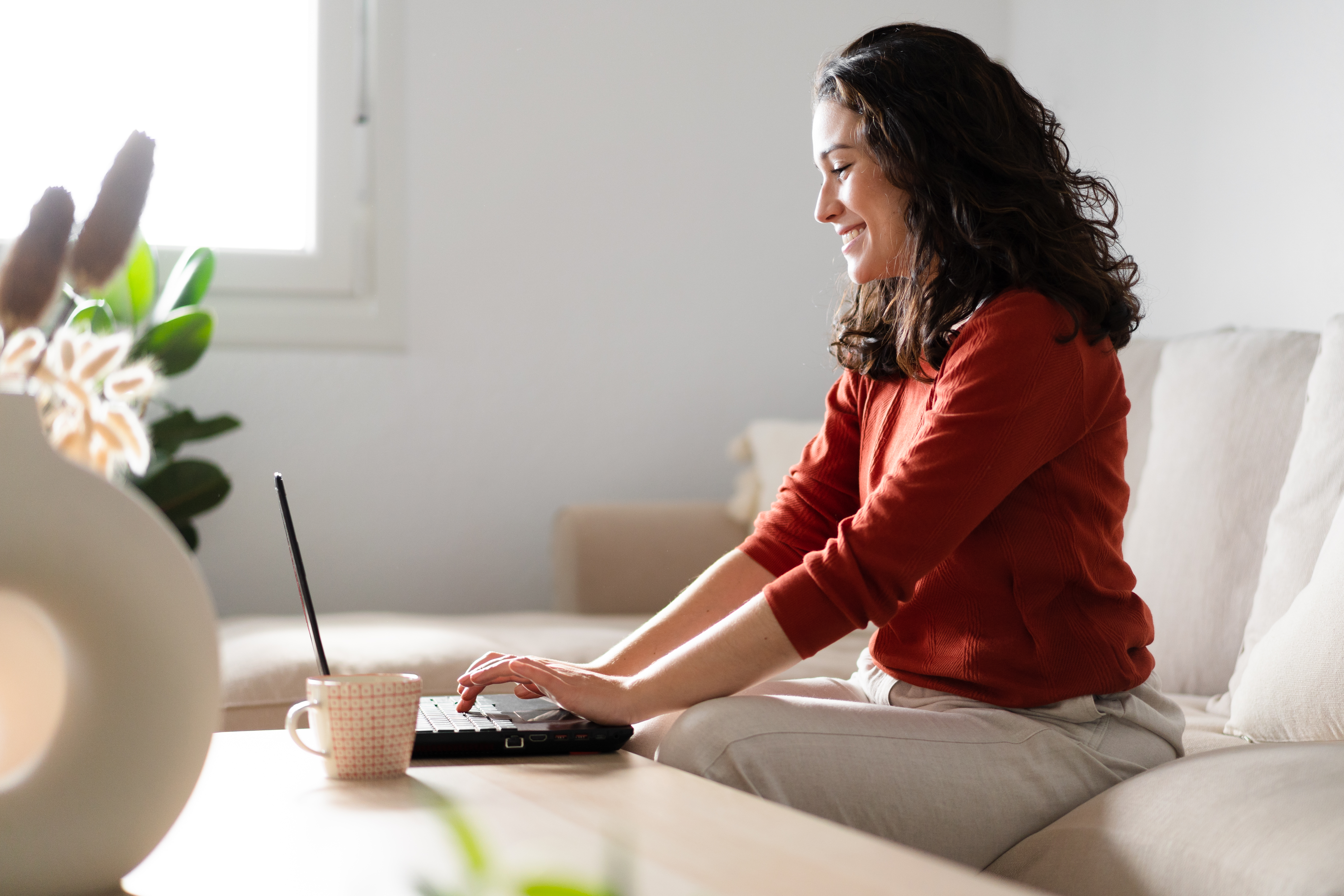 happy-young-woman-using-laptop-sitting-on-the-couch
