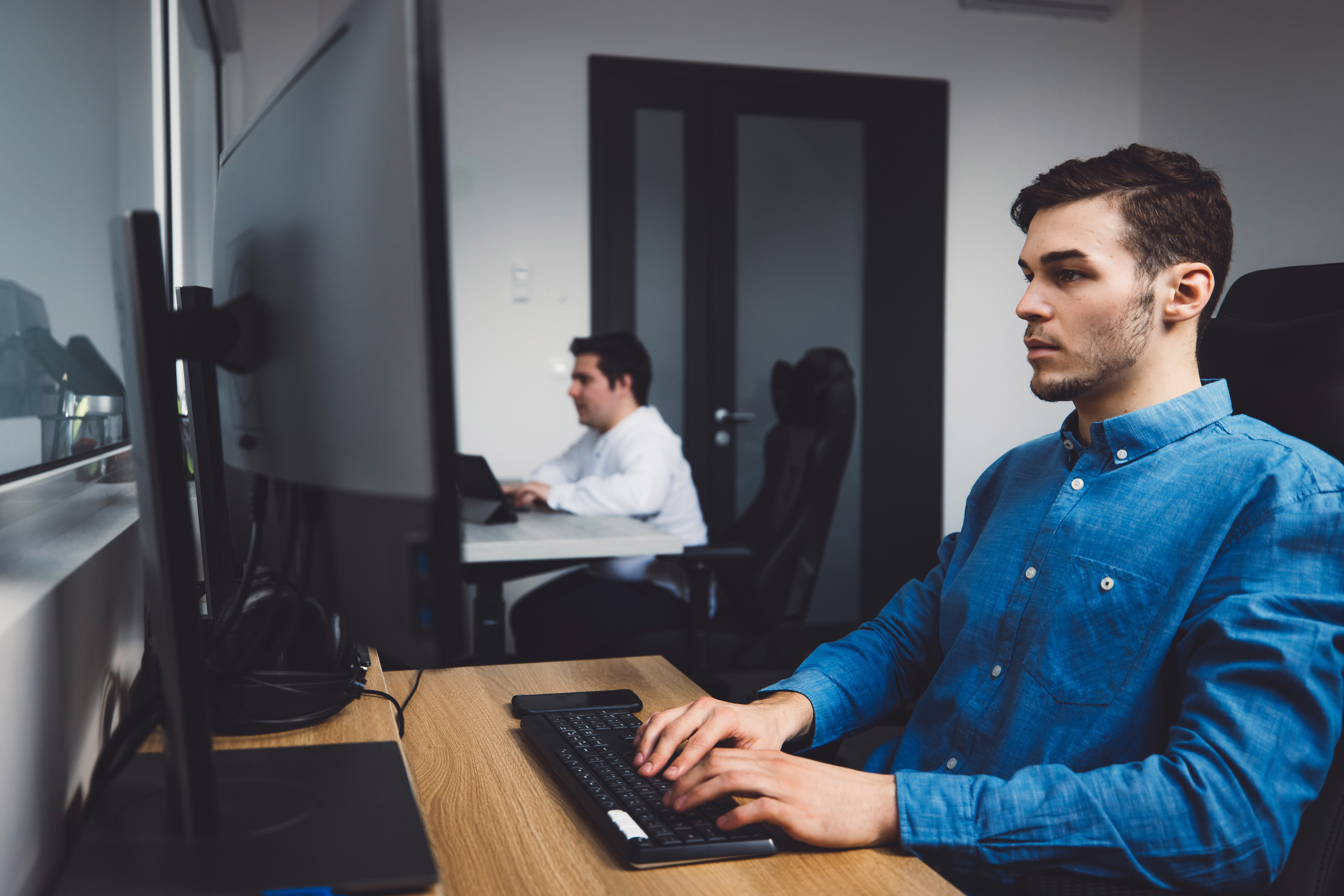 side-view-two-programmers-working-in-the-office-coding-on-desk-top-computers