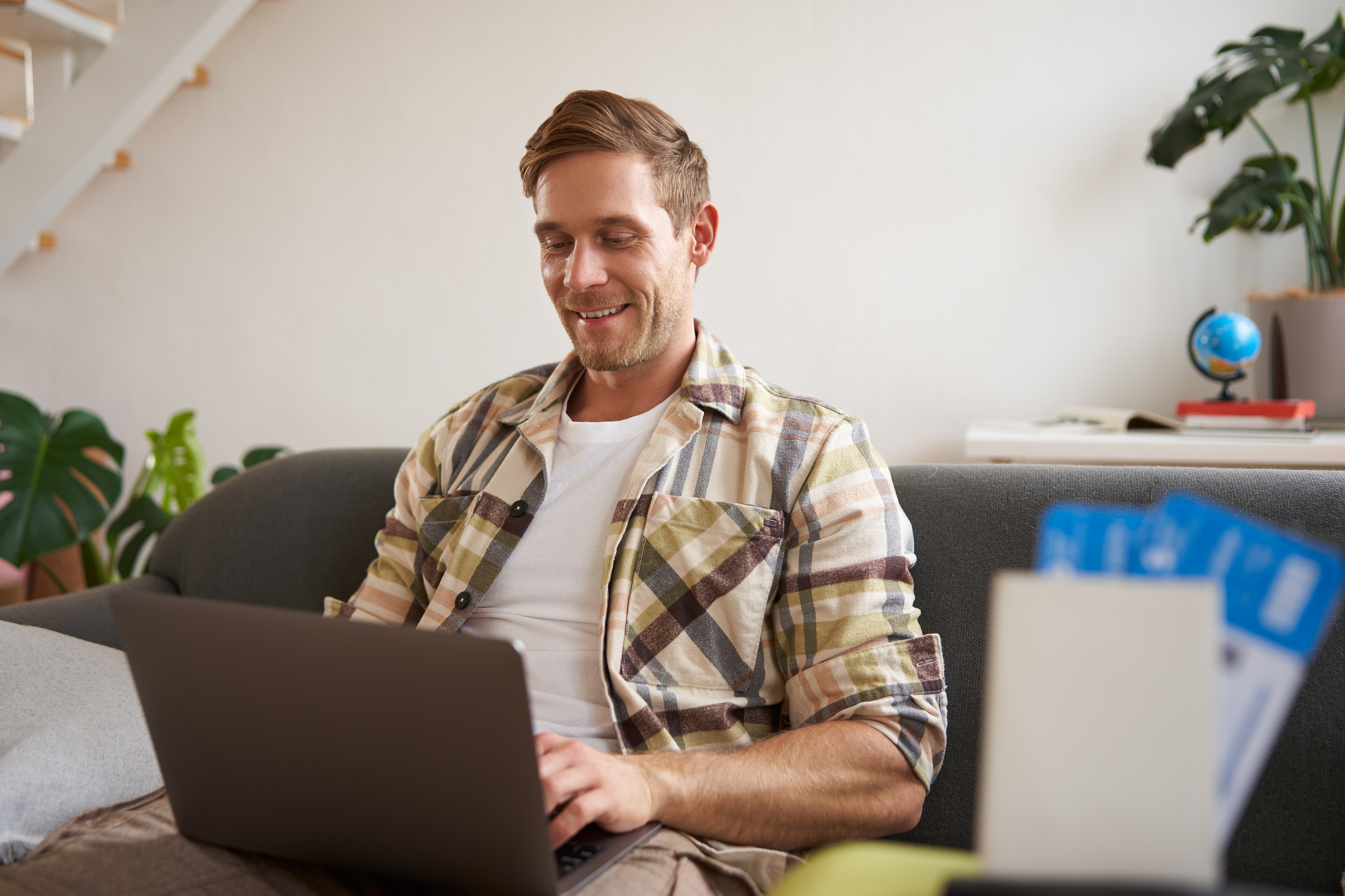 portrait-of-young-handsome-man-sitting-with-laptop-has-passport-and-two-plane-tickets-prepared-planning-his-journey-on-computer-booking-hotels-and-restaurants-online-for-the-trip