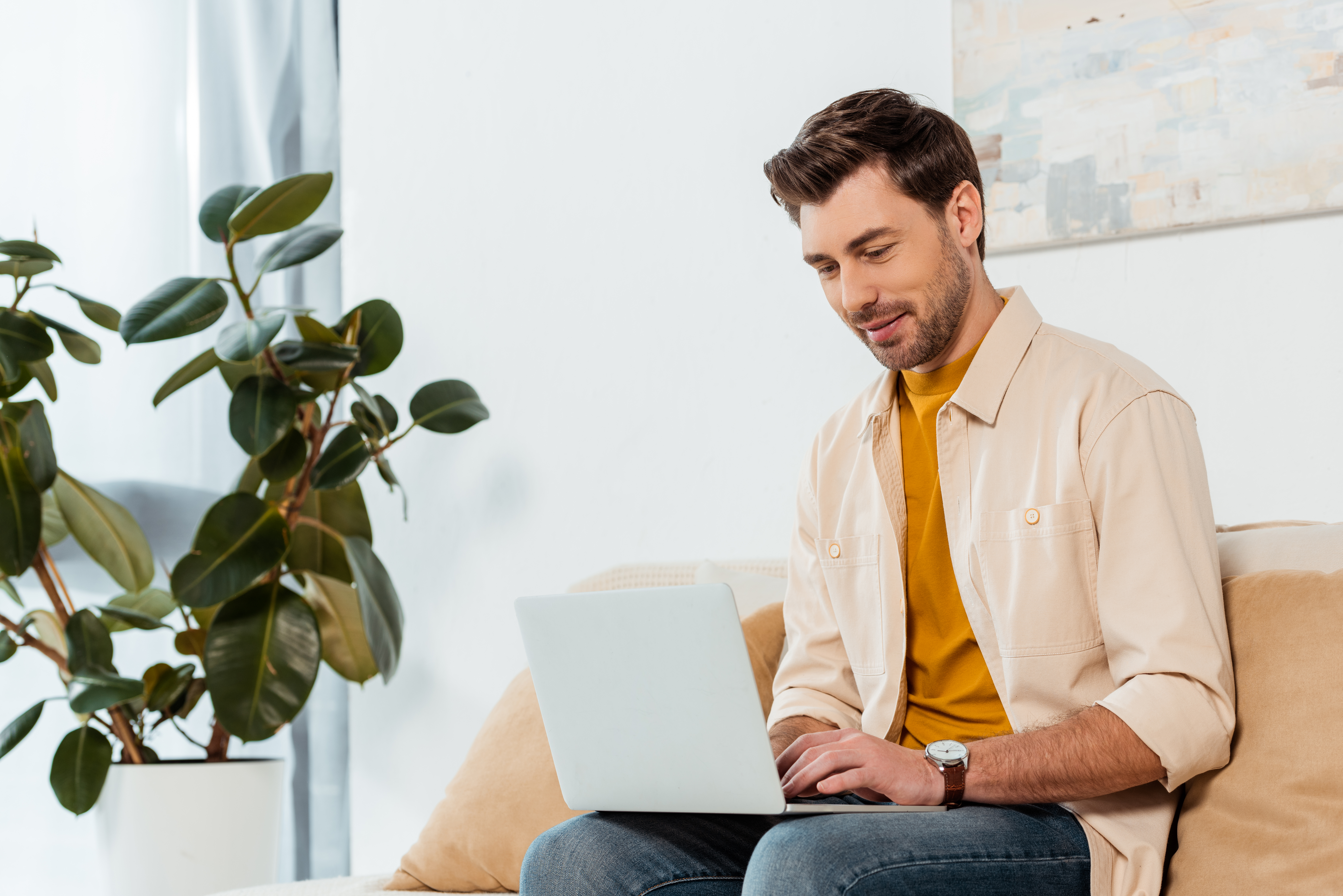 handsome-freelancer-using-laptop-in-living-room
