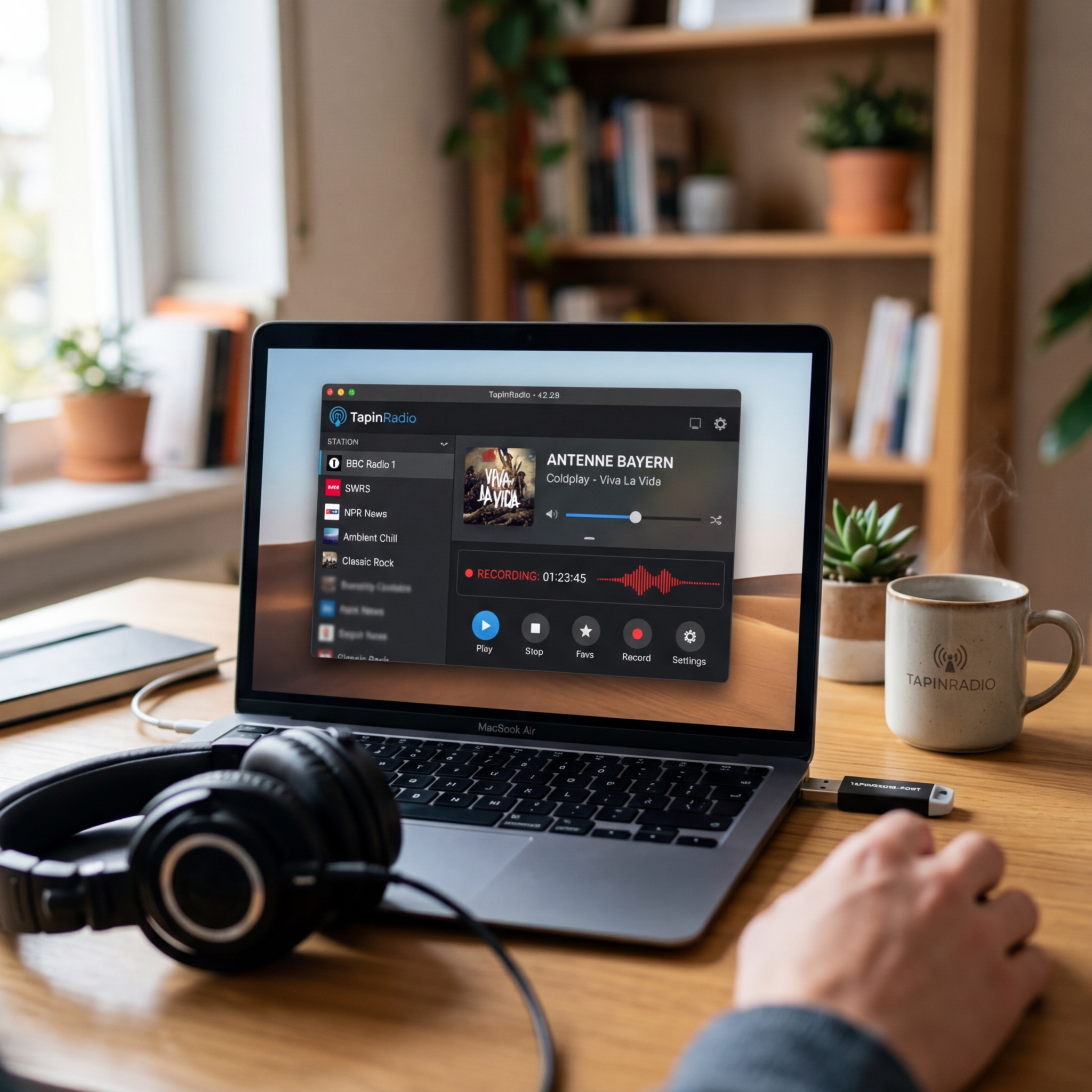 Laptop mit TapinRadio App, Kopfhörer und Tasse auf einem Tisch